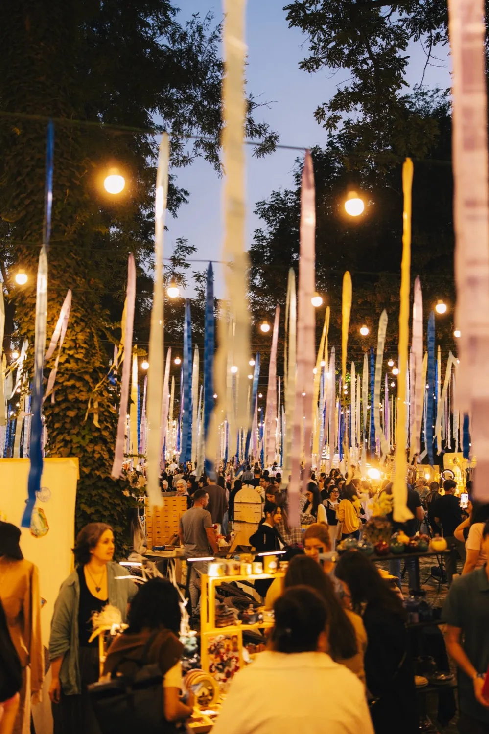 Teplo Fest at dusk — pale streamers and string lights above the crowd